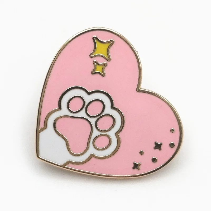Pin de esmalte duro de un corazón rosa con una huella de pata blanca y destellos dorados