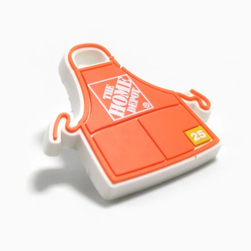 Pin de PVC naranja con forma de delantal de trabajo, hecho para una cadena de artículos para el hogar y construcción.