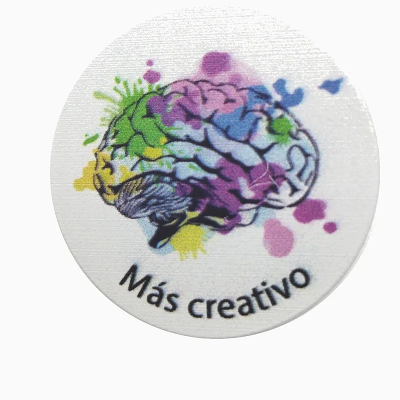 Pin redondo con impresión UV de un cerebro con salpicaduras de pintura de colores y el texto Más creativo sobre fondo blanco