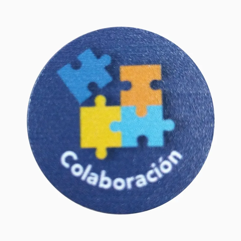 Pin redondo azul marino con impresión UV de piezas de rompecabezas entrelazadas y el texto Colaboración en blanco