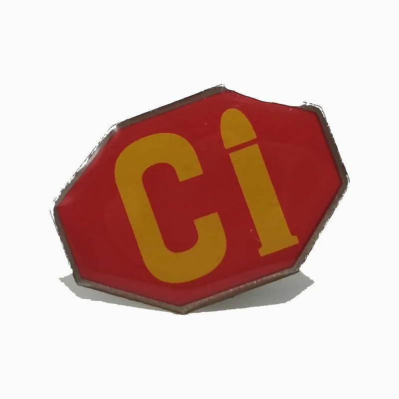 Pin impreso octagonal con el texto Ci en amarillo sobre fondo rojo bajo una capa de epoxi transparente
