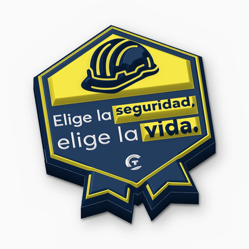 Pin hexagonal de PVC suave azul marino y amarillo sobre seguridad con un casco y el texto Elige la seguridad, elige la vida