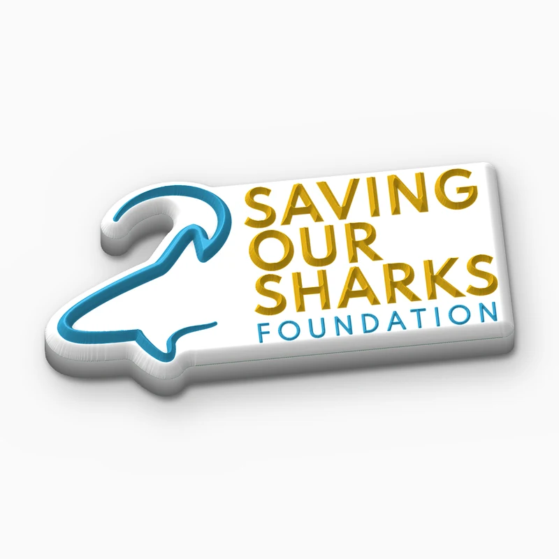 Pin recortado de PVC suave blanco con la silueta de un tiburón azul y el texto Saving Our Sharks Foundation