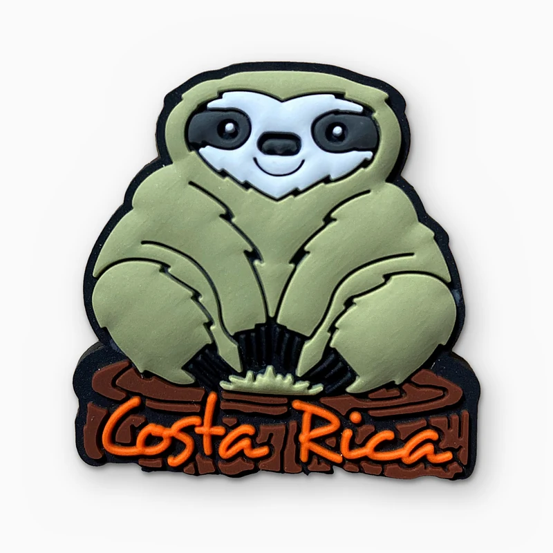 Pin de PVC suave de un perezoso con detalles en capas y relieve, sentado sobre un tronco, con el texto Costa Rica en naranja