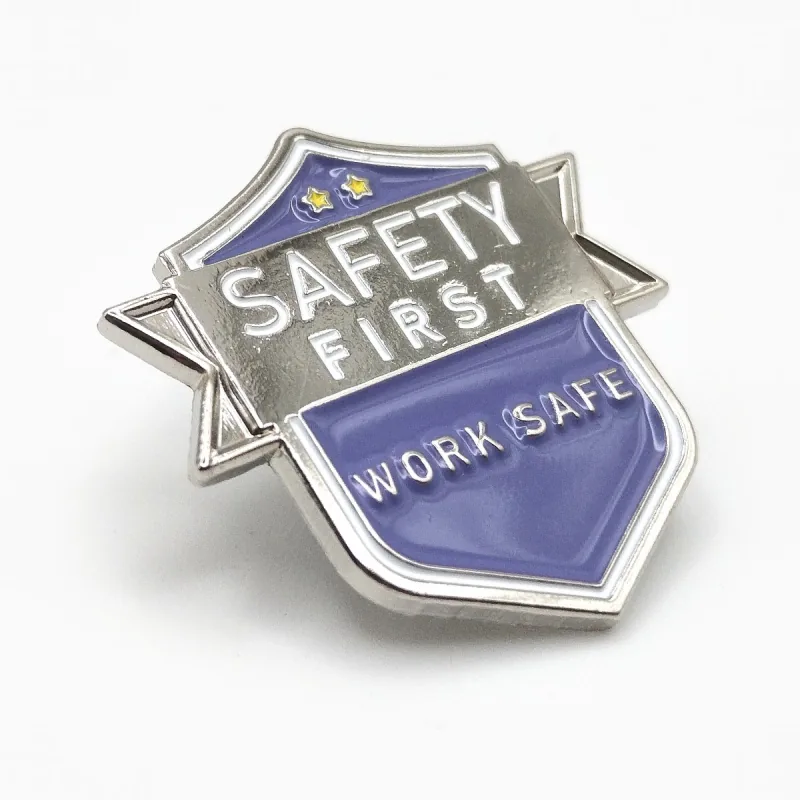 Pin de esmalte suave en forma de escudo con baño de níquel, una banda plateada «Safety First» y un escudo morado «Work Safe».