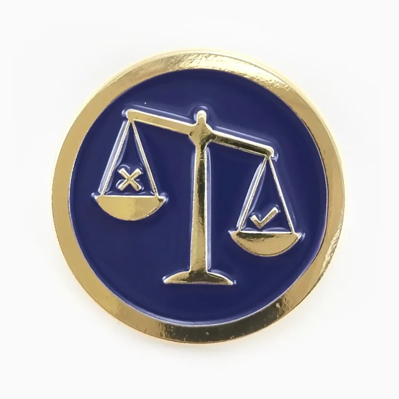 Pin redondo de esmalte suave con baño dorado y una balanza de la justicia en relieve sobre esmalte azul marino.