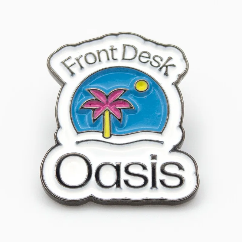 Pin de esmalte suave en níquel negro con el texto Front Desk Oasis, una palmera rosa y un sol sobre esmalte azul
