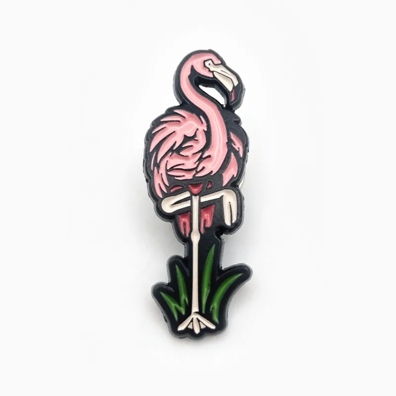 Pin recortado de esmalte suave de un flamenco rosa parado sobre hojas verdes