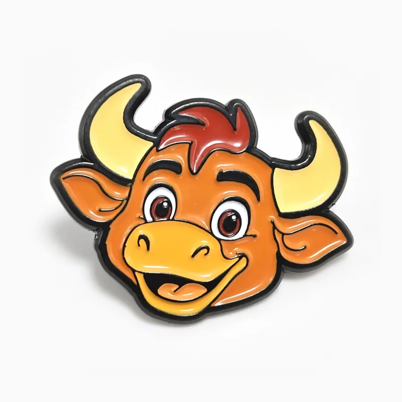 Pin troquelado de esmalte suave de una cabeza de toro caricaturesca naranja y sonriente con cuernos amarillos, en níquel negro.