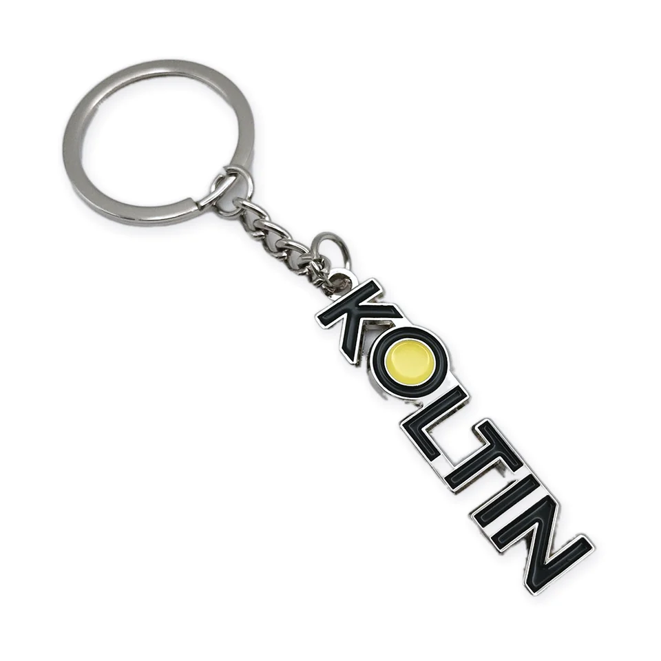 Llavero de metal con letras recortadas en esmalte negro que forman KOLTIN y una O amarilla, con argolla y cadena.