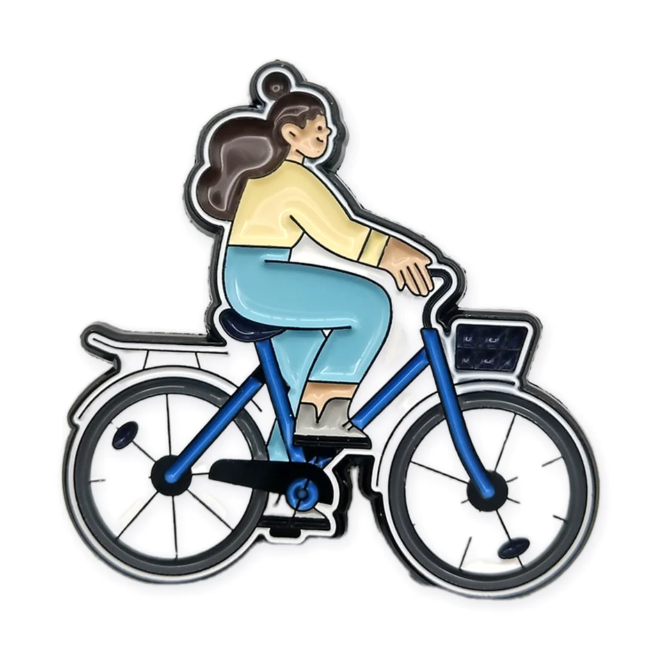 Llavero de esmalte suave de una mujer en bicicleta azul con canasta.