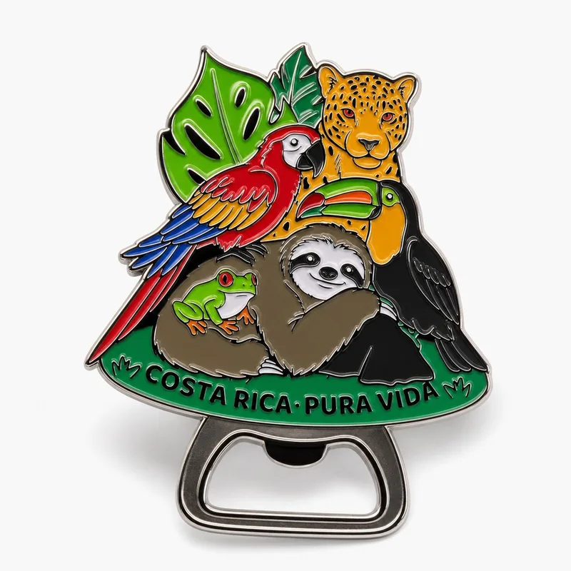 Destapador de metal con una guacamaya, un jaguar, un tucán, un perezoso y una rana entre hojas, sobre una base verde con el texto Costa Rica Pura Vida.